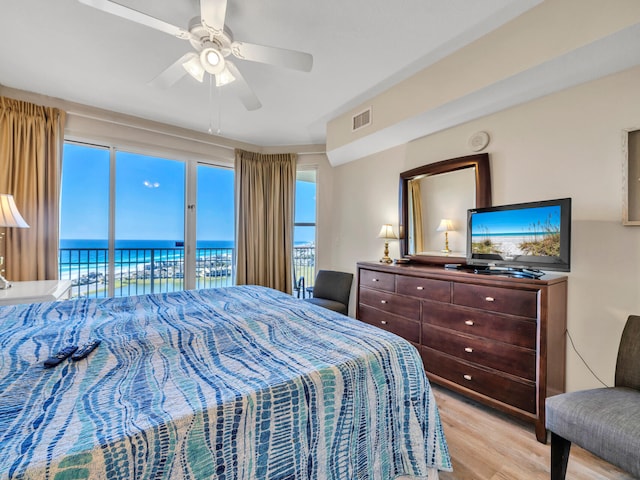 bedroom with access to exterior, ceiling fan, a water view, and light hardwood / wood-style floors