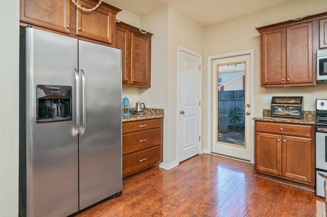 kitchen with dark stone countertops, stainless steel fridge, dark hardwood / wood-style flooring, and range