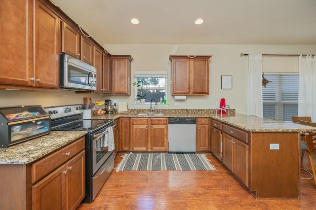 kitchen with sink, dark hardwood / wood-style flooring, kitchen peninsula, a breakfast bar, and appliances with stainless steel finishes