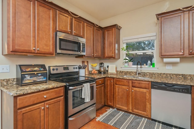 kitchen with hardwood / wood-style floors, sink, stainless steel appliances, and stone counters