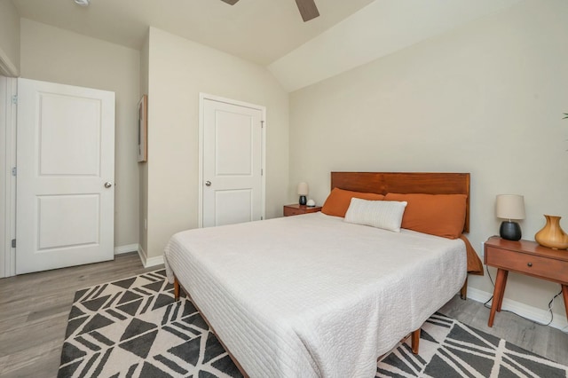 bedroom featuring ceiling fan, light wood-type flooring, and lofted ceiling