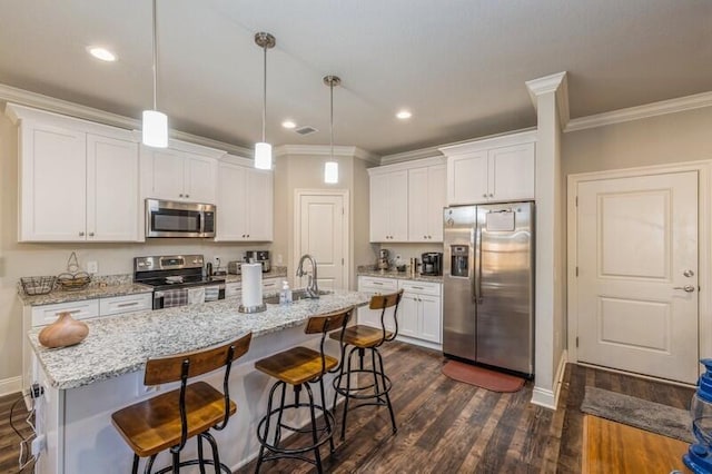 kitchen featuring white cabinets, pendant lighting, stainless steel appliances, and a kitchen island with sink