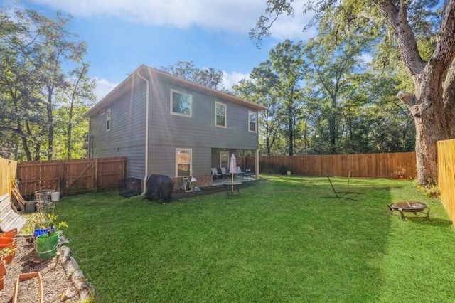 back of property featuring a fire pit, a patio area, and a yard