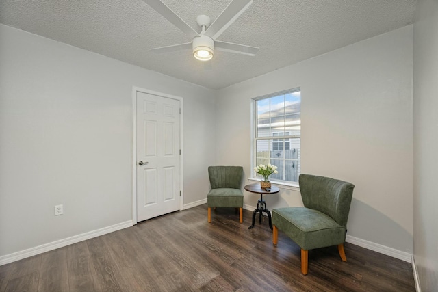 living area featuring a textured ceiling, dark hardwood / wood-style floors, and ceiling fan