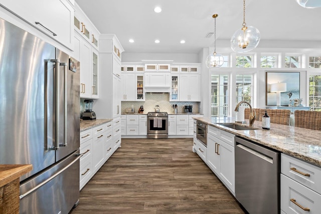 kitchen featuring white cabinets, sink, dark hardwood / wood-style floors, decorative light fixtures, and stainless steel appliances