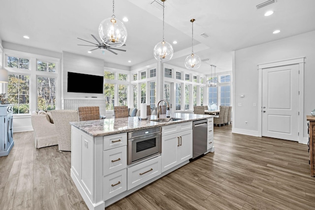 kitchen with wood-type flooring, white cabinetry, an island with sink, and hanging light fixtures