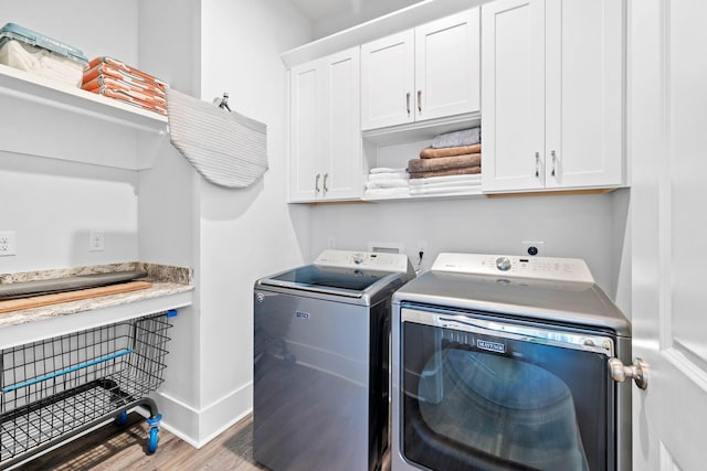 washroom featuring washing machine and clothes dryer, cabinets, and hardwood / wood-style flooring