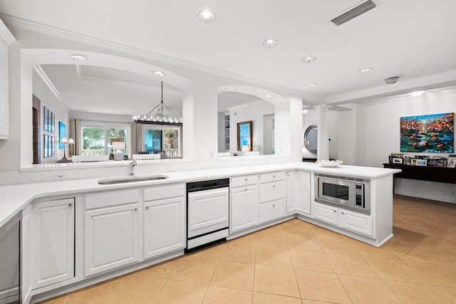 kitchen with kitchen peninsula, white cabinets, stainless steel microwave, and sink