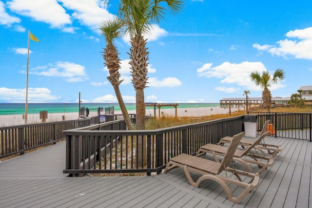 wooden terrace featuring a water view and a view of the beach