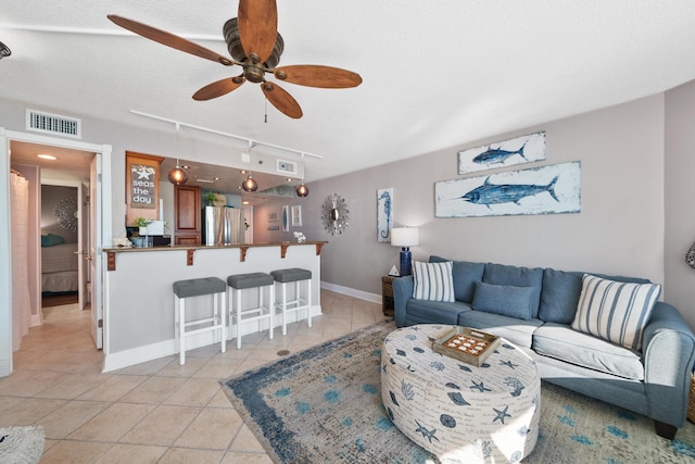 living room with ceiling fan, light tile patterned floors, a textured ceiling, and track lighting