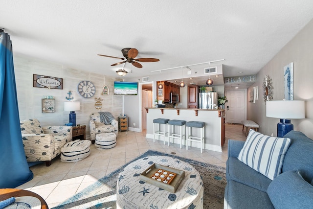 living room featuring ceiling fan, light tile patterned floors, rail lighting, and a textured ceiling