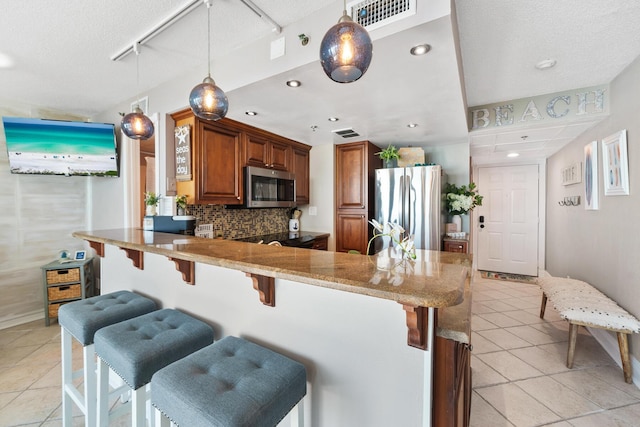 kitchen featuring a breakfast bar area, kitchen peninsula, pendant lighting, and stainless steel appliances