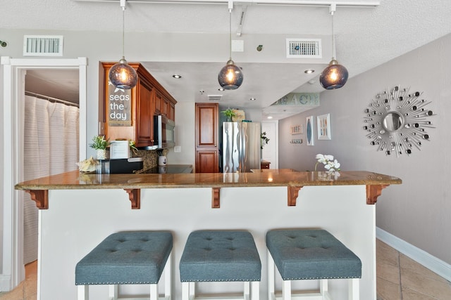 kitchen with a kitchen breakfast bar, hanging light fixtures, light tile patterned floors, appliances with stainless steel finishes, and kitchen peninsula