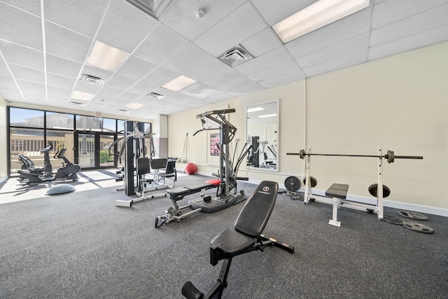 exercise room with a drop ceiling and expansive windows