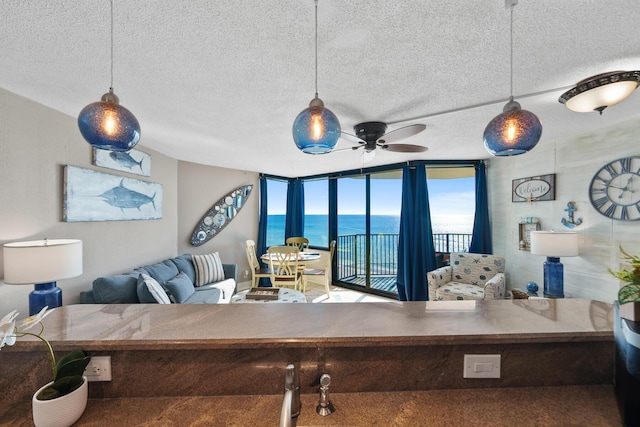 9850 S Thomas Dr Unit 1004W, Panama City Beach, FL 32408 - living area featuring a textured ceiling, a ceiling fan, and a water view