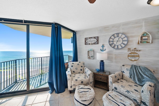 living room featuring floor to ceiling windows, a water view, and a textured ceiling