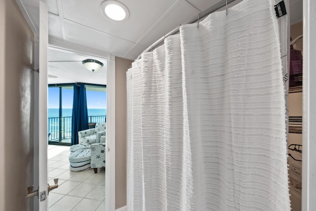 bathroom with tile patterned flooring, a water view, and a wall of windows