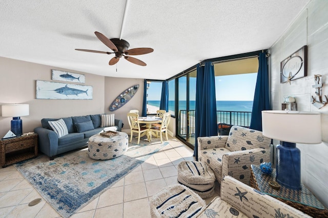 tiled living room featuring a textured ceiling, a water view, expansive windows, and ceiling fan