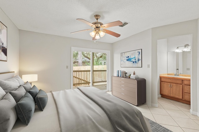 bedroom with light tile patterned floors, ensuite bathroom, access to outside, a textured ceiling, and a sink