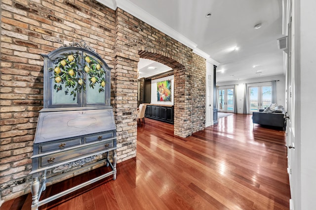 corridor featuring hardwood / wood-style floors, crown molding, and brick wall