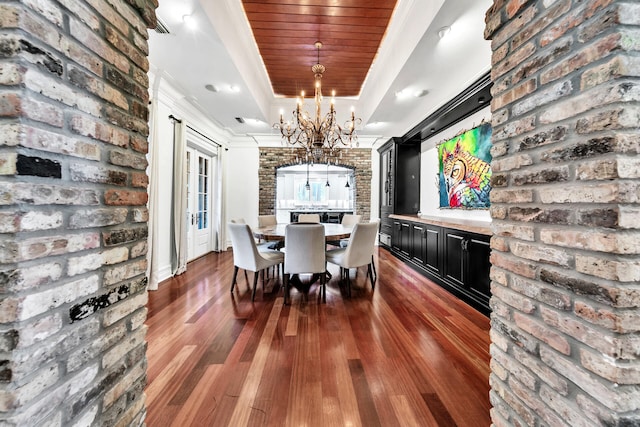 dining area featuring wooden ceiling, dark wood-type flooring, an inviting chandelier, ornamental molding, and brick wall