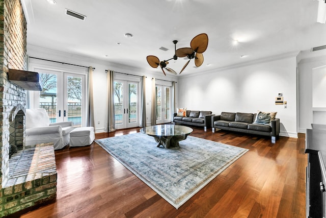 living room with a brick fireplace, french doors, dark hardwood / wood-style floors, and ornamental molding