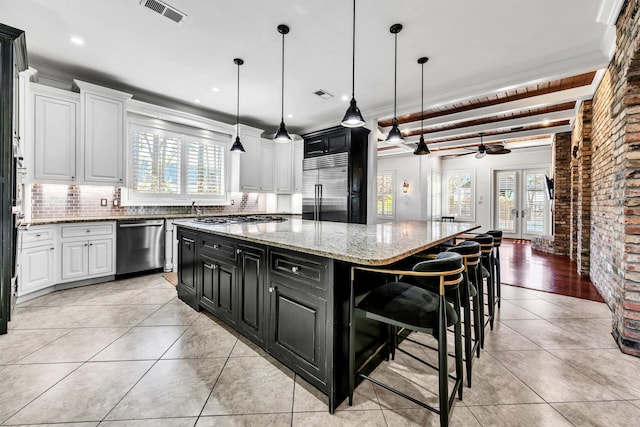 kitchen with white cabinets, ceiling fan, a spacious island, and stainless steel appliances