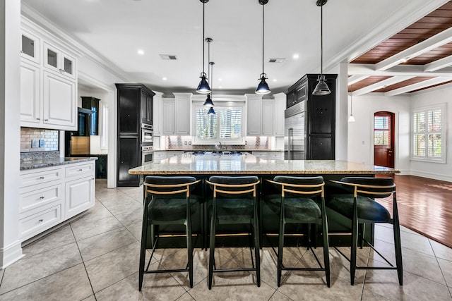 kitchen featuring a kitchen breakfast bar, a spacious island, and light stone countertops