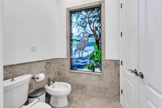 bathroom with toilet, a bidet, tile patterned floors, and tile walls