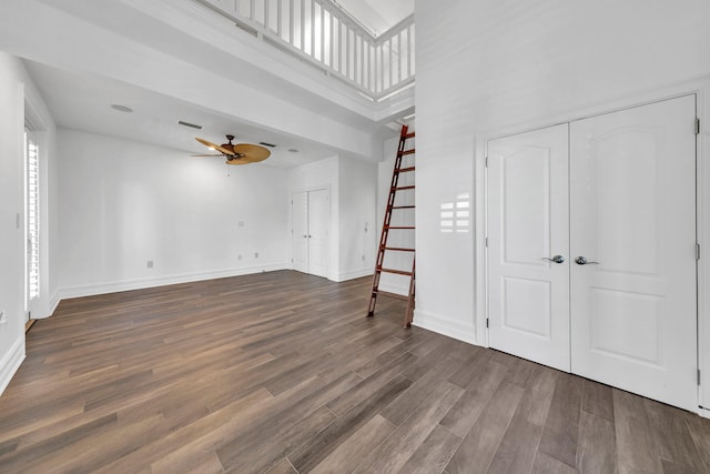 unfurnished living room with a towering ceiling, dark hardwood / wood-style floors, and ceiling fan