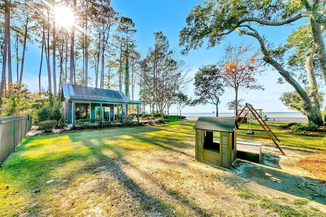 view of yard with a playground, an outbuilding, and a water view