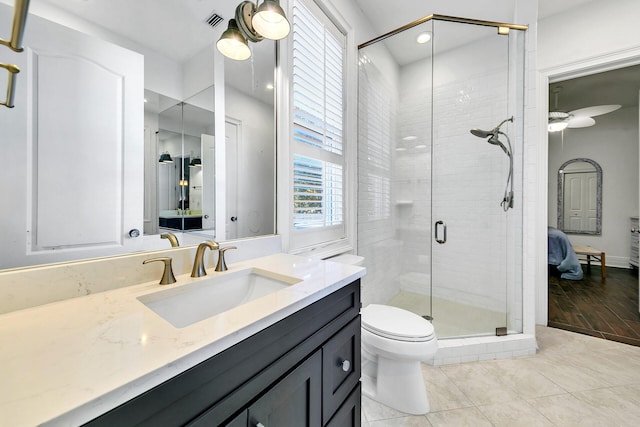 bathroom with ceiling fan, tile patterned floors, toilet, vanity, and a shower with shower door