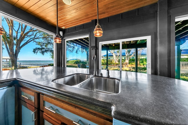 kitchen with pendant lighting, sink, a water view, and wood ceiling