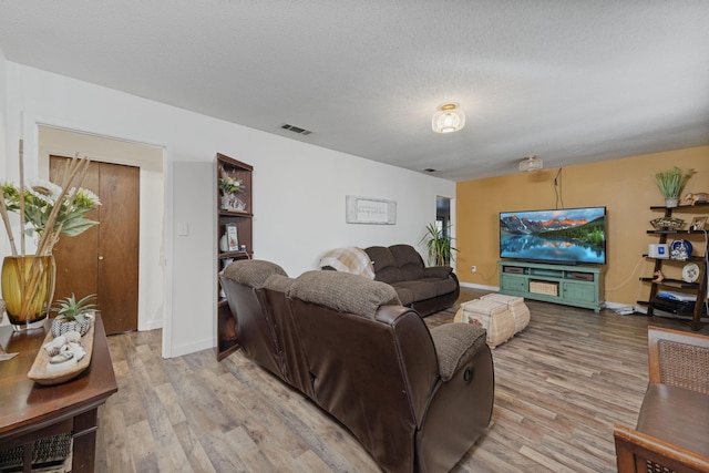 living room featuring a textured ceiling and light wood-type flooring