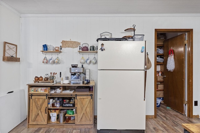 kitchen with wood walls, hardwood / wood-style floors, white fridge, and crown molding