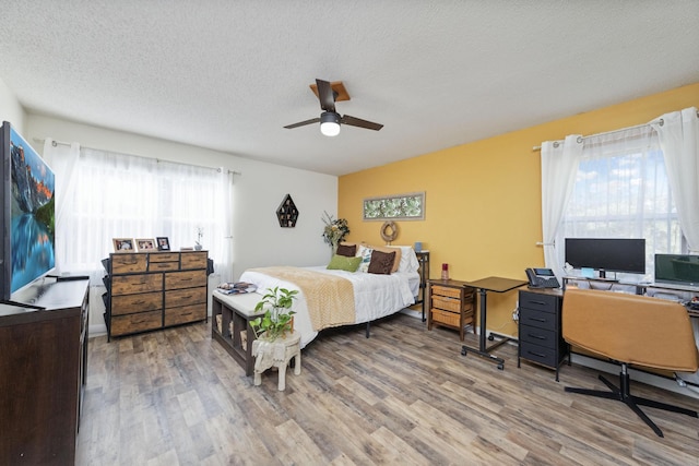 bedroom featuring hardwood / wood-style flooring, ceiling fan, and a textured ceiling