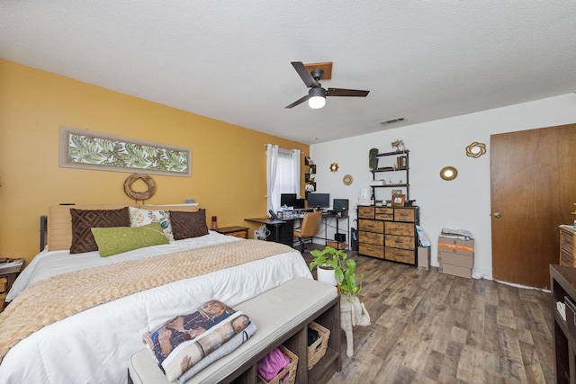 bedroom with ceiling fan, hardwood / wood-style floors, and a textured ceiling