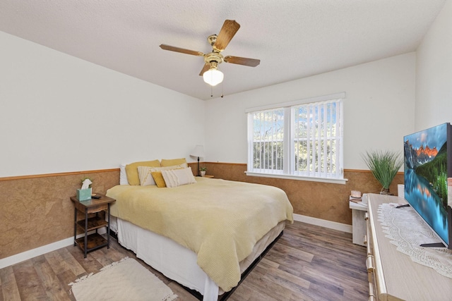 bedroom featuring ceiling fan, wood walls, a textured ceiling, and hardwood / wood-style flooring