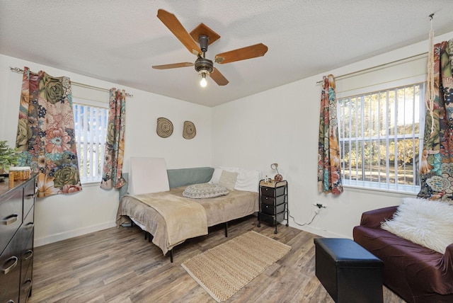 bedroom with a textured ceiling, hardwood / wood-style flooring, and ceiling fan