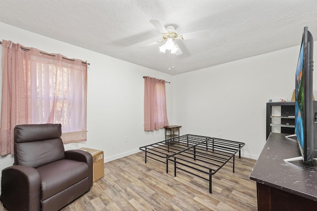 living area featuring a textured ceiling, light hardwood / wood-style flooring, and ceiling fan