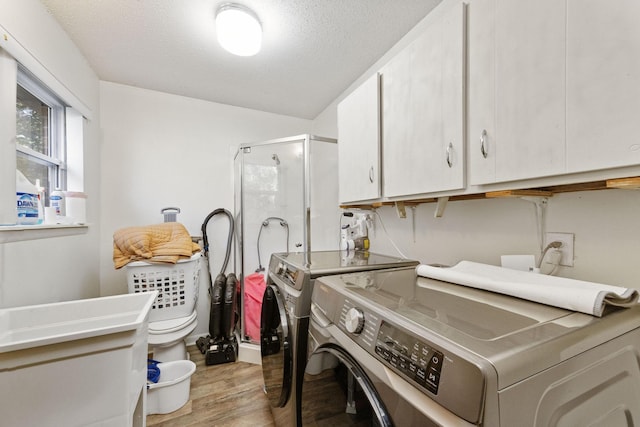 washroom with separate washer and dryer, a textured ceiling, and light hardwood / wood-style flooring