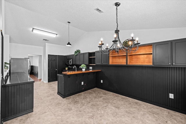 kitchen featuring a notable chandelier, kitchen peninsula, stainless steel appliances, and hanging light fixtures