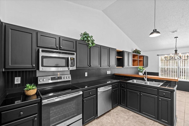 kitchen with a textured ceiling, decorative light fixtures, sink, and appliances with stainless steel finishes