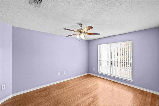 unfurnished room with ceiling fan, wood-type flooring, and a textured ceiling