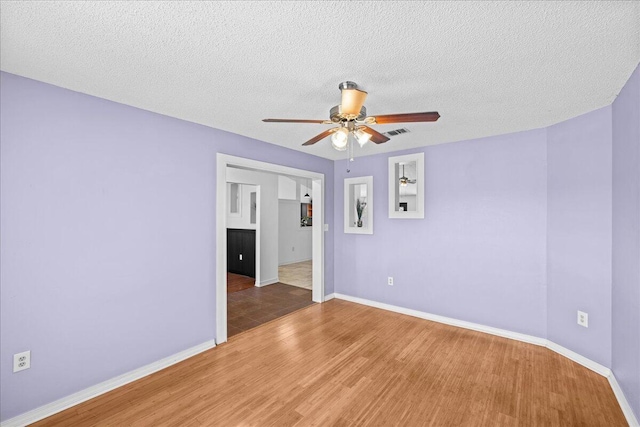 unfurnished room with hardwood / wood-style floors, ceiling fan, and a textured ceiling