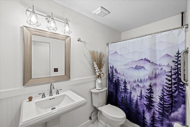 bathroom with a textured ceiling, toilet, and sink