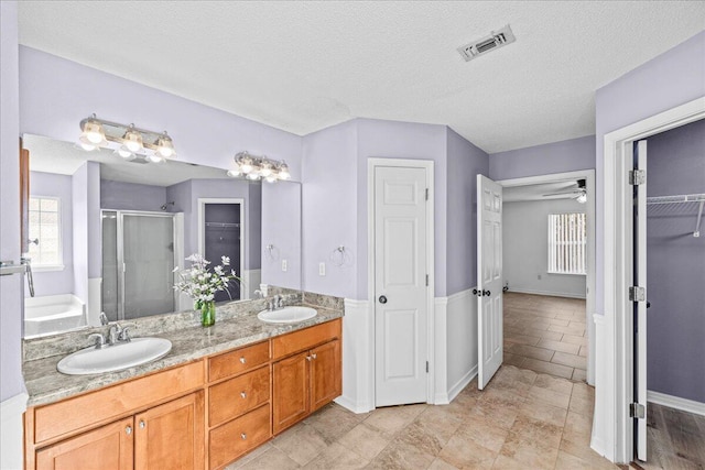 bathroom featuring vanity, a textured ceiling, walk in shower, and ceiling fan