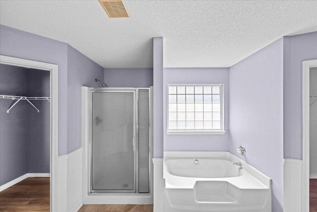 bathroom featuring a textured ceiling, hardwood / wood-style flooring, and separate shower and tub