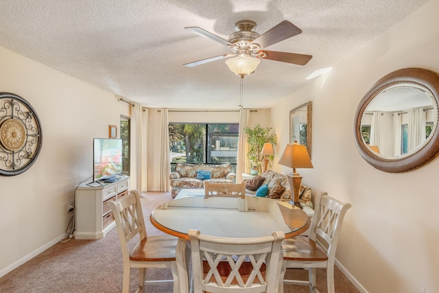 dining space with a textured ceiling, light colored carpet, and ceiling fan