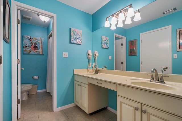 bathroom with toilet, vanity, and tile patterned floors